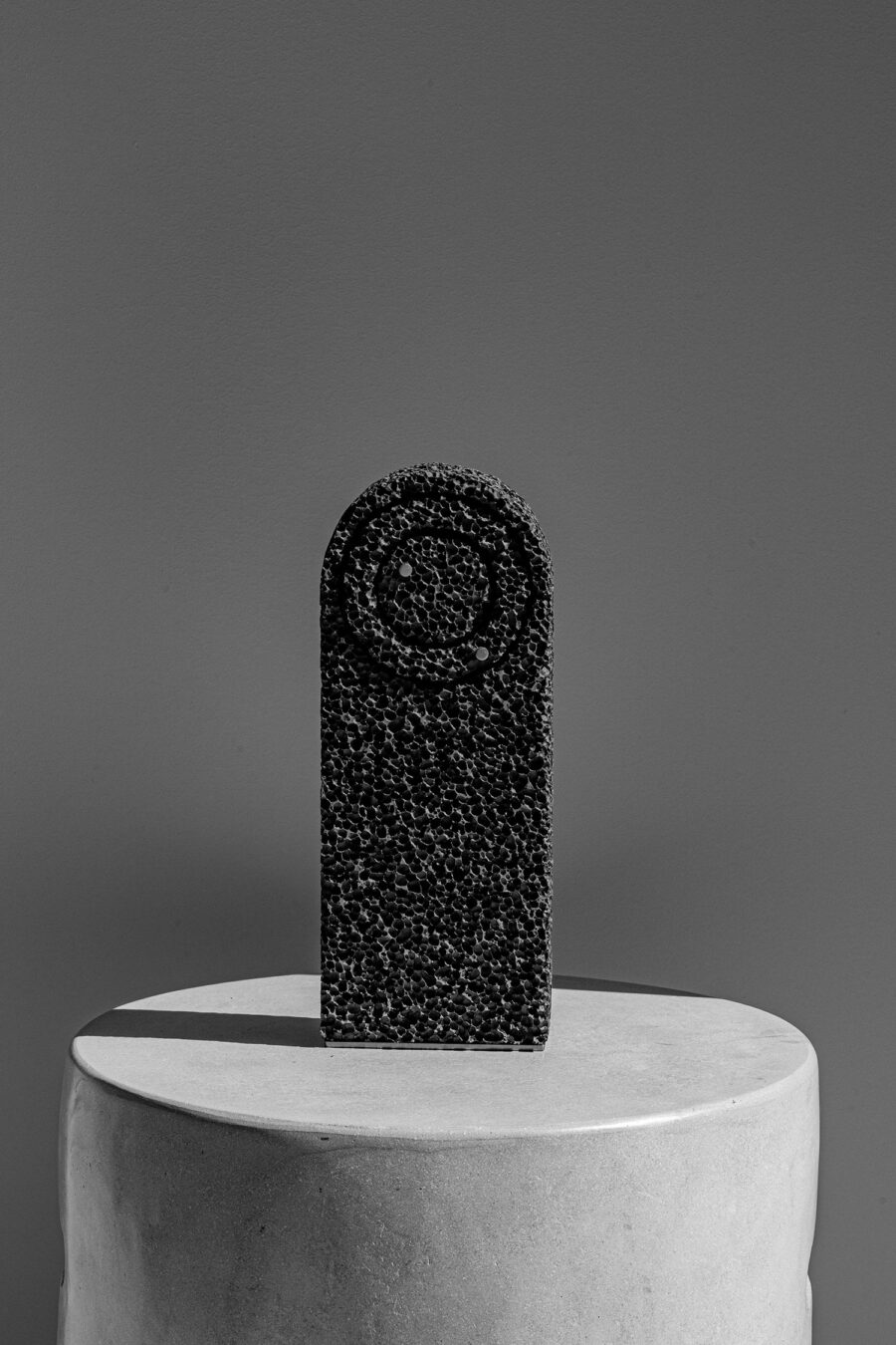 Studio Michael McCready From Foam To Dust Table Clock on a stone plinth casting shadow to the left side