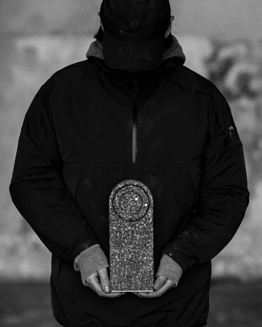 Studio Michael McCready From Foam to Dust Table Clock held in the hand of a dark figure presumably the creator of the art