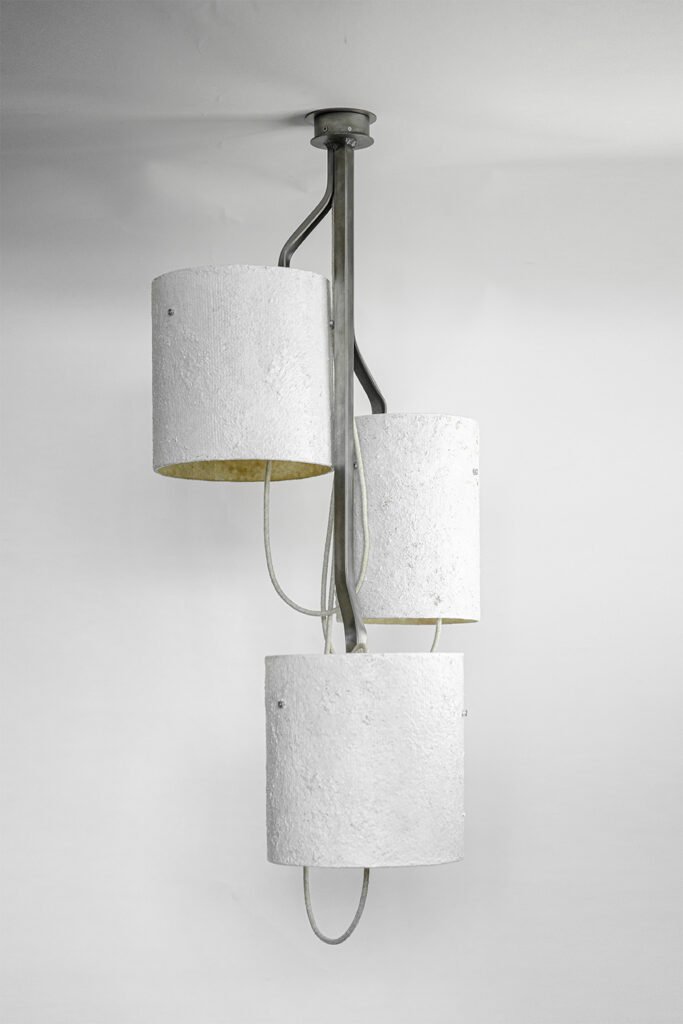 Ceiling-mounted light with three white stone-effect shades on curved metallic arms extending from a central frame. Mounted on a circular ceiling rose, it blends minimalism with artistry.